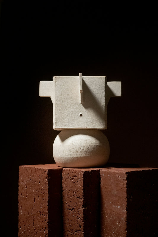 a white sculpture sitting on top of a brick wall
