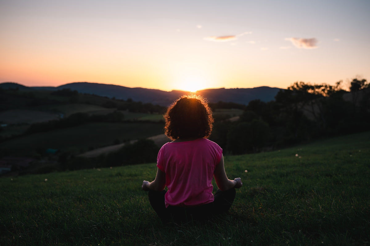 woman squatting in grass during golden hour