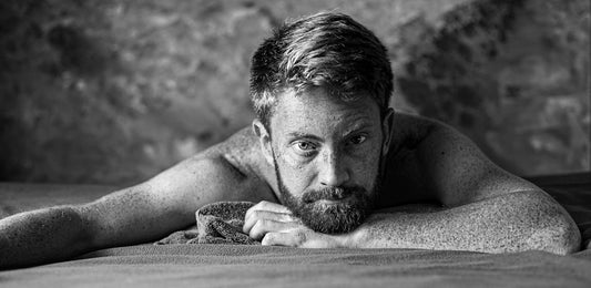 grayscale photo of man leaning on wall