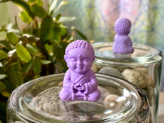 a small buddha statue sitting on top of a jar