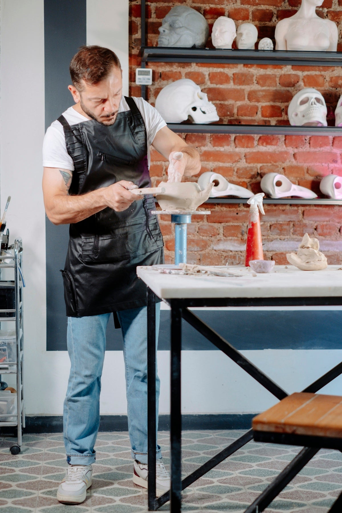 A man in an apron is making clay sculptures