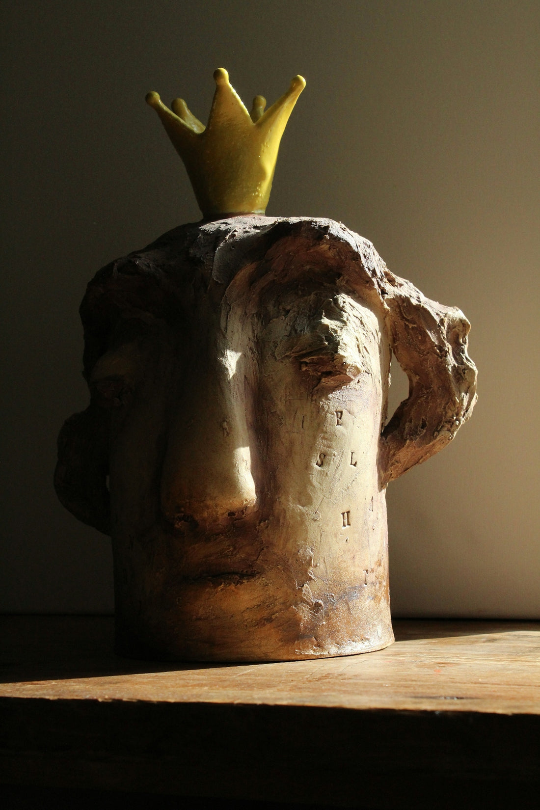A clay sculpture of a head adorned with a crown.