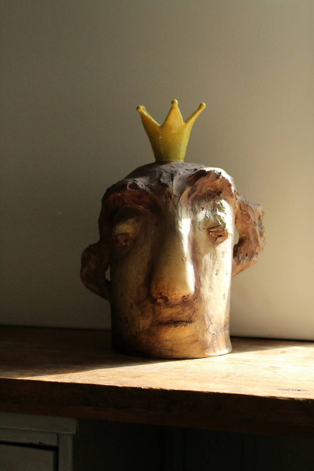 A ceramic head sculpture wears a small crown.