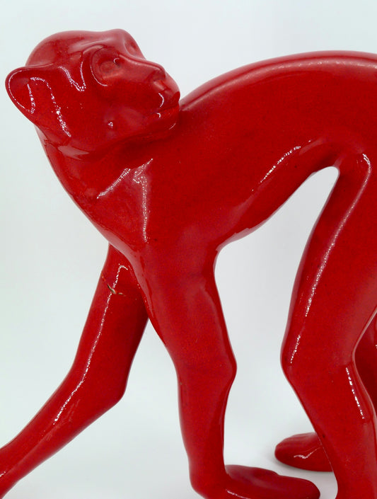 A shiny red monkey sculpture on a white background.