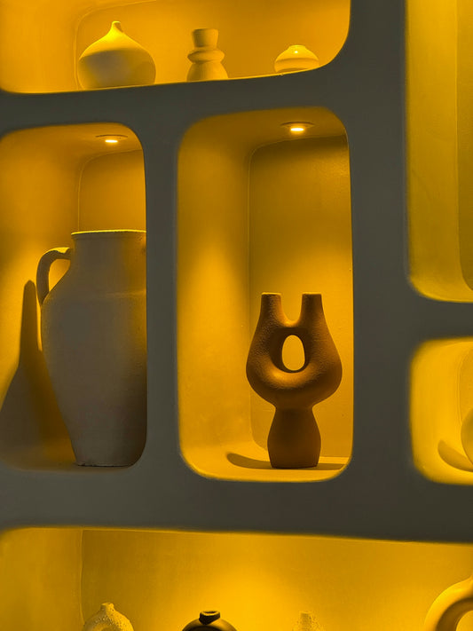 Ceramic vases and sculptures displayed in illuminated niches.
