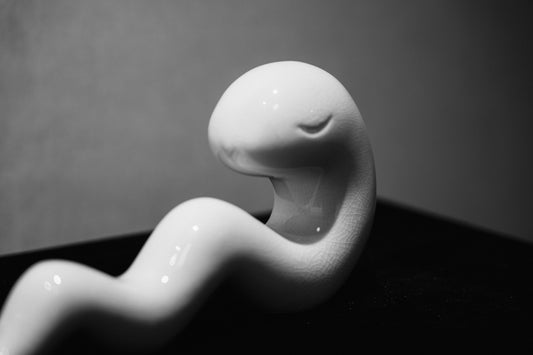 A white ceramic snake sculpture with closed eyes.