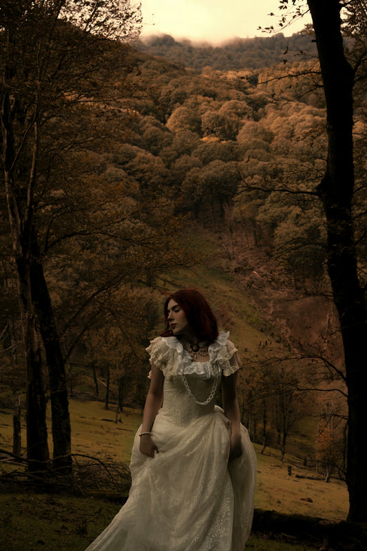 Woman in vintage dress in autumnal forest landscape