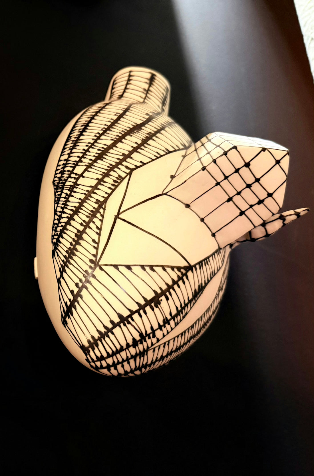 Ceramic heart sculpture with intricate black line patterns.