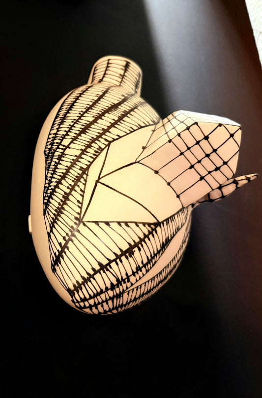 Ceramic heart sculpture with intricate black line patterns.